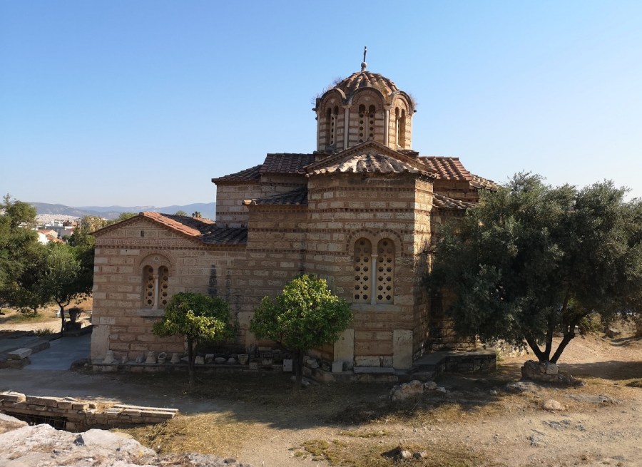 A Greek Orthodox Church with towers and dome next to Olive trees