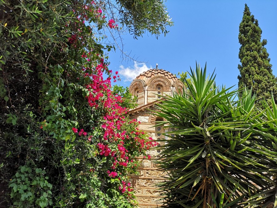 The domed roof of a very old Greek Orthodox Church amongst pretty bouganvillia and spiky trees