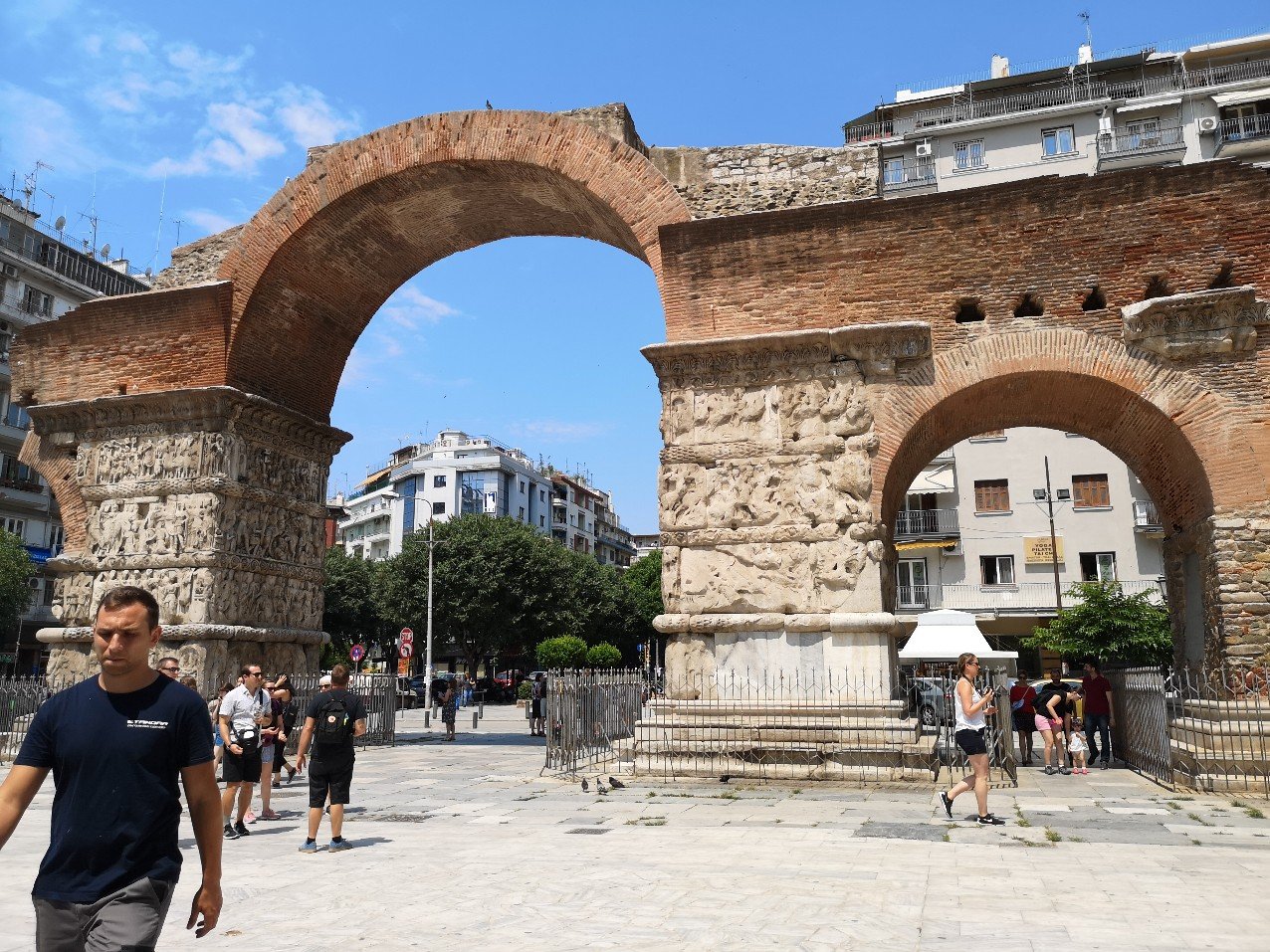 Soft coloured stone arch with blue sky and buildings visible through 