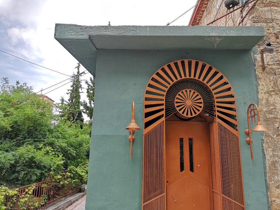 Ornate orange door in a green wall with lamp outside 